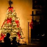 Lit Christmas tree with red bows in a dark room