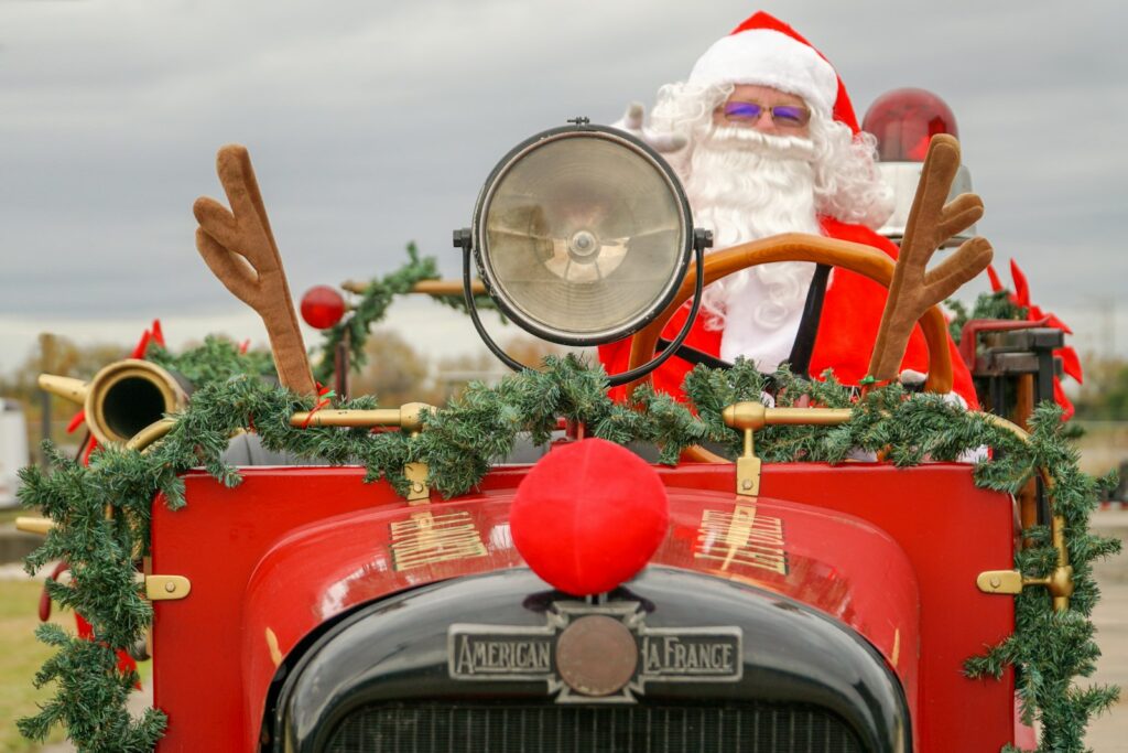 Santa Claus in a vintage red car decorated with garland